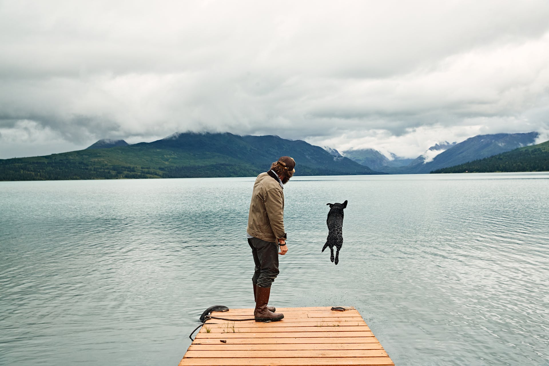 Man standing at the edge of a dock playing with his dog wearing Filson Bremerton Work Pants