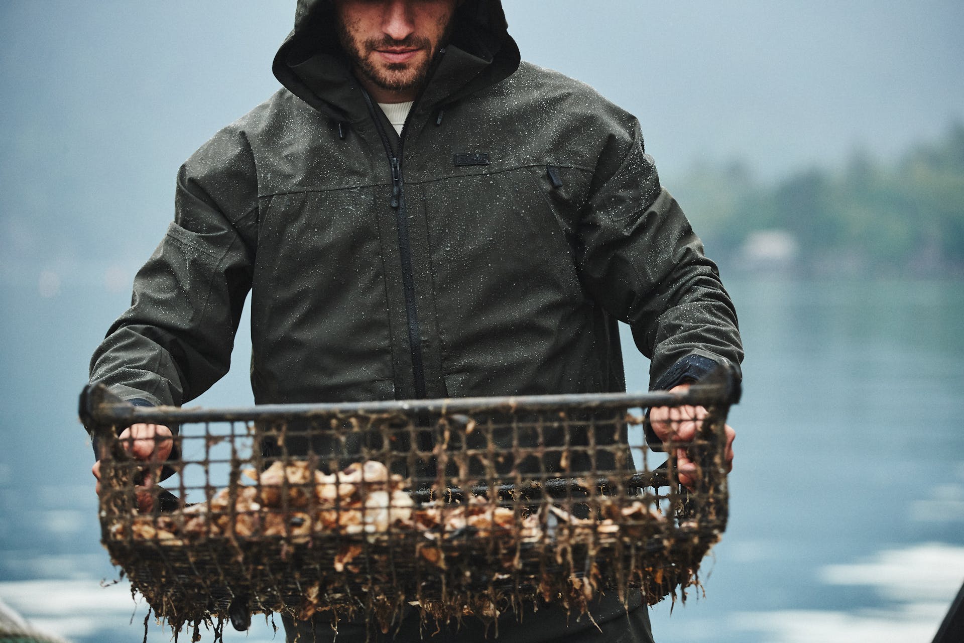 Man wearing Filson Skagit Rain Jacket in peat inspecting basket of caught seafood
