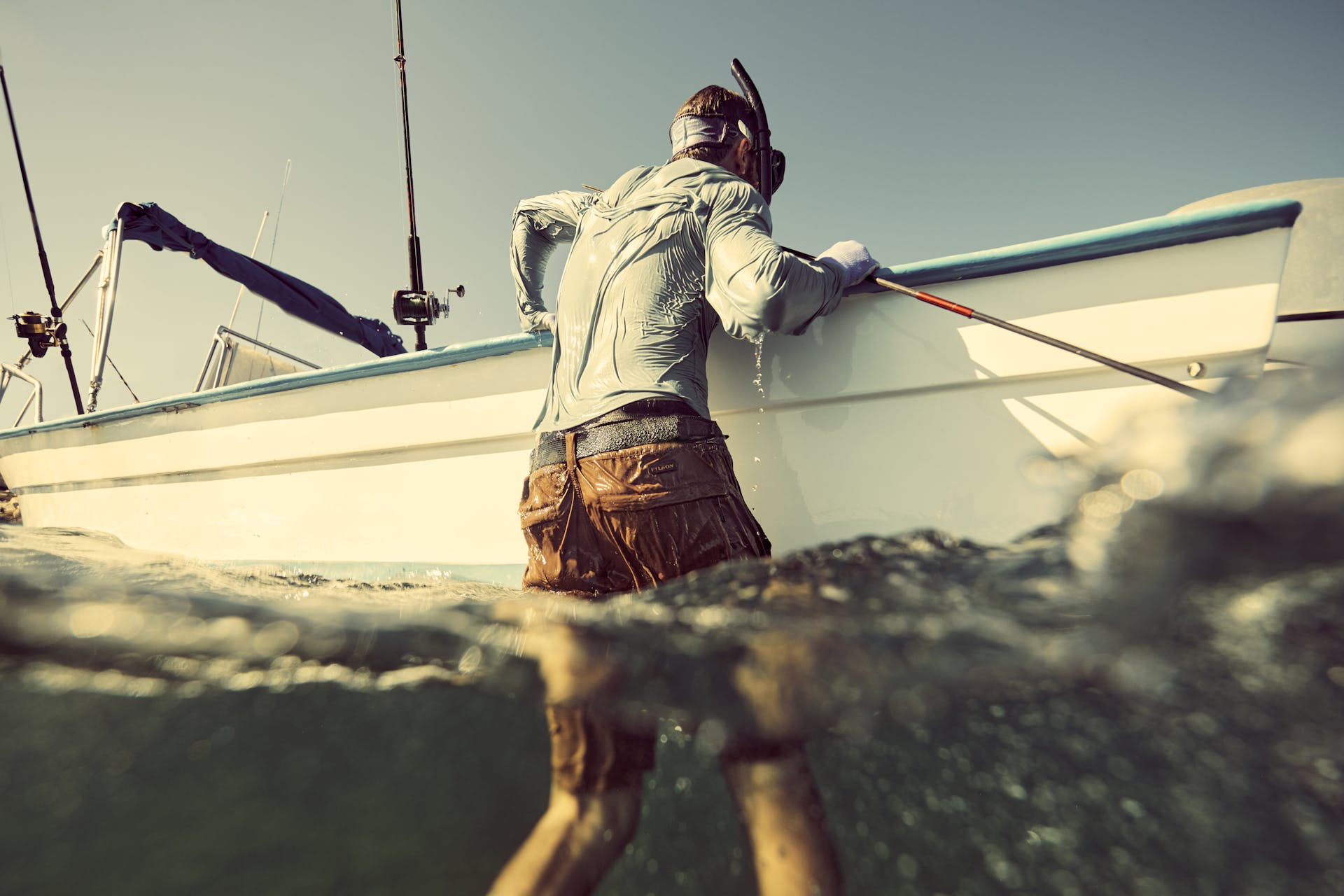 Man climbing into a boat in the ocean wearing a Filson Long Sleeve Barrier T-Shirt