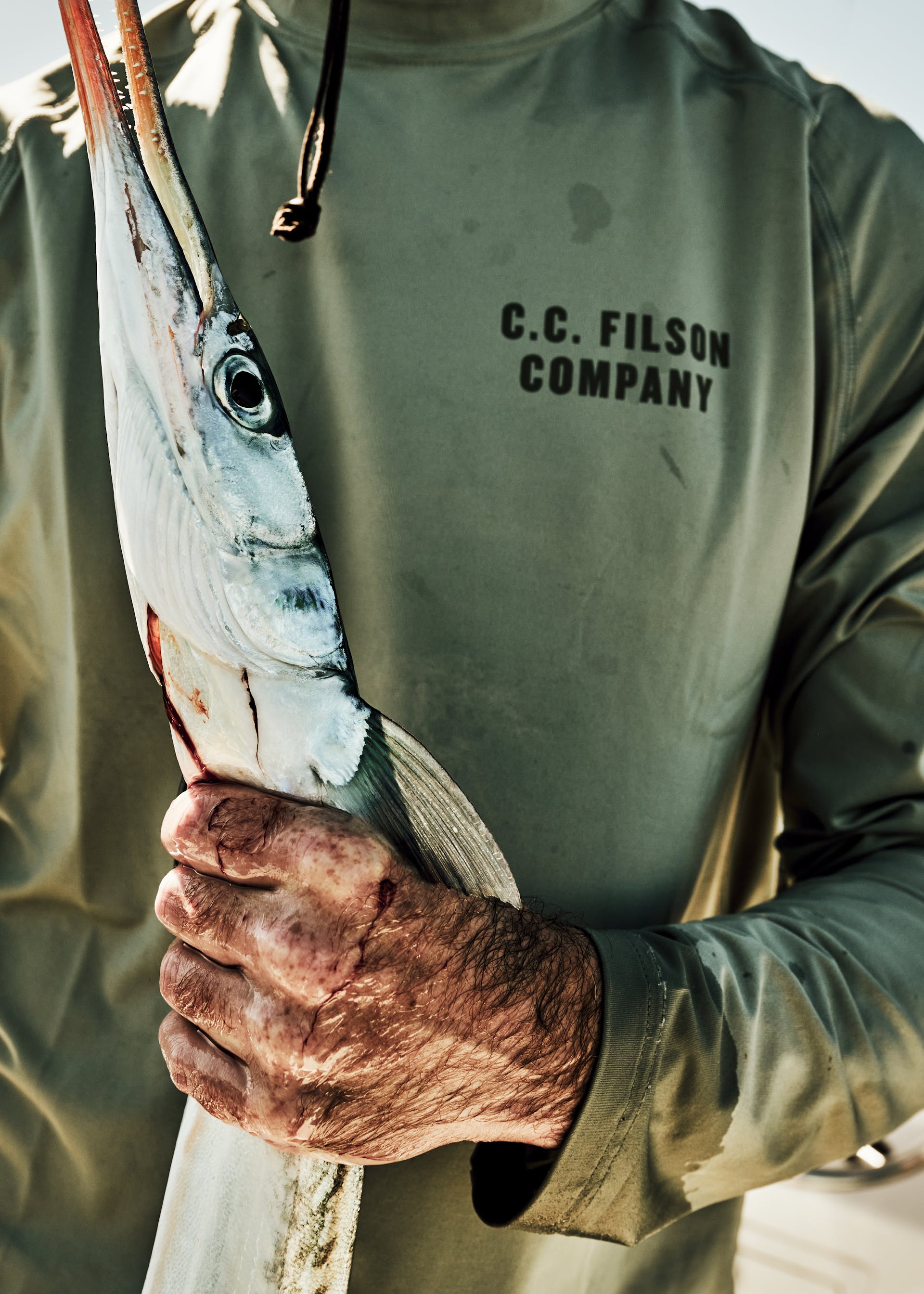 Fisherman holding a fish wearing a FIlson Long Sleeve Barrier T-Shirt