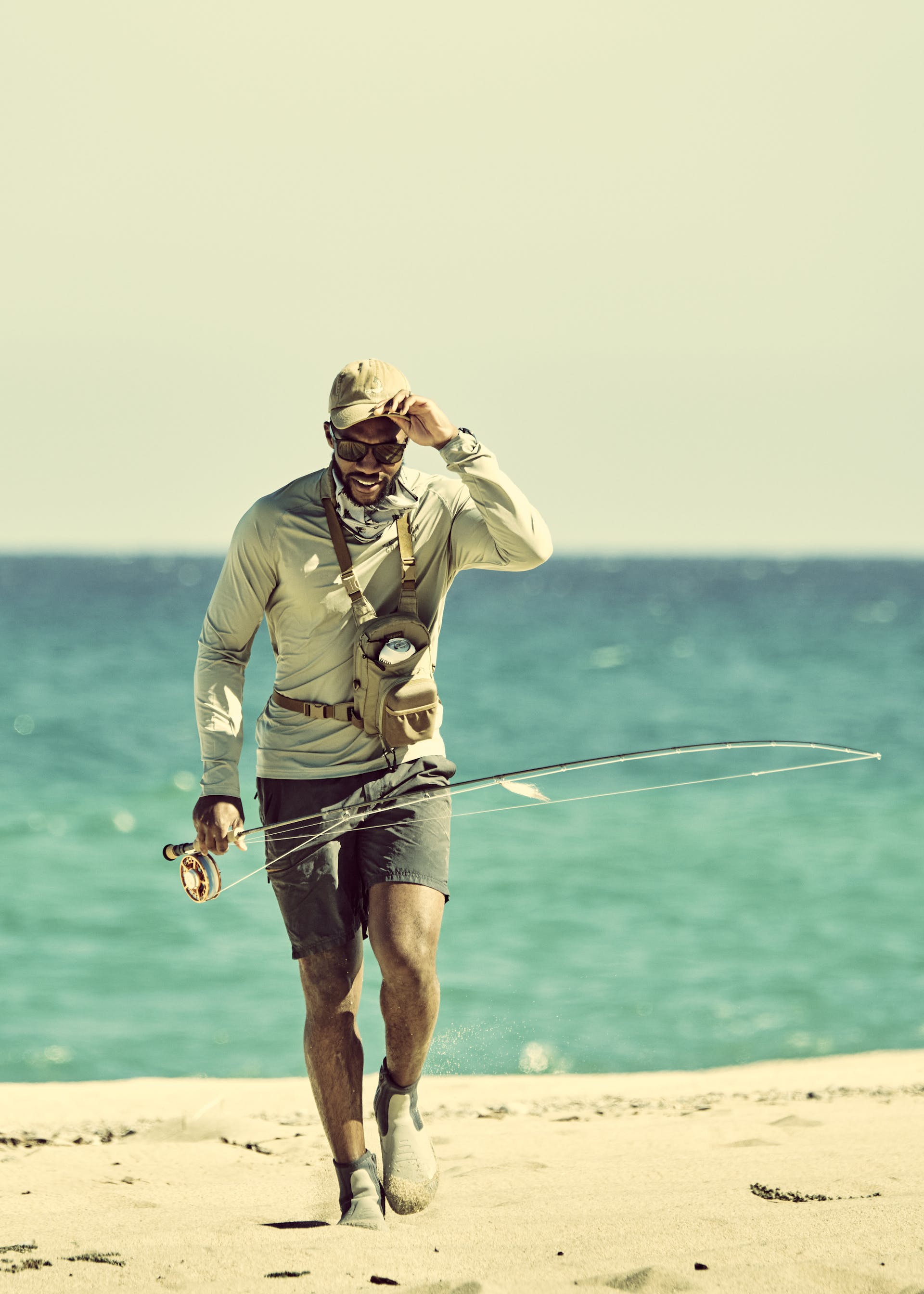 Fisherman walking on the beach wearing a Filson Long Sleeve Barrier T-Shirt