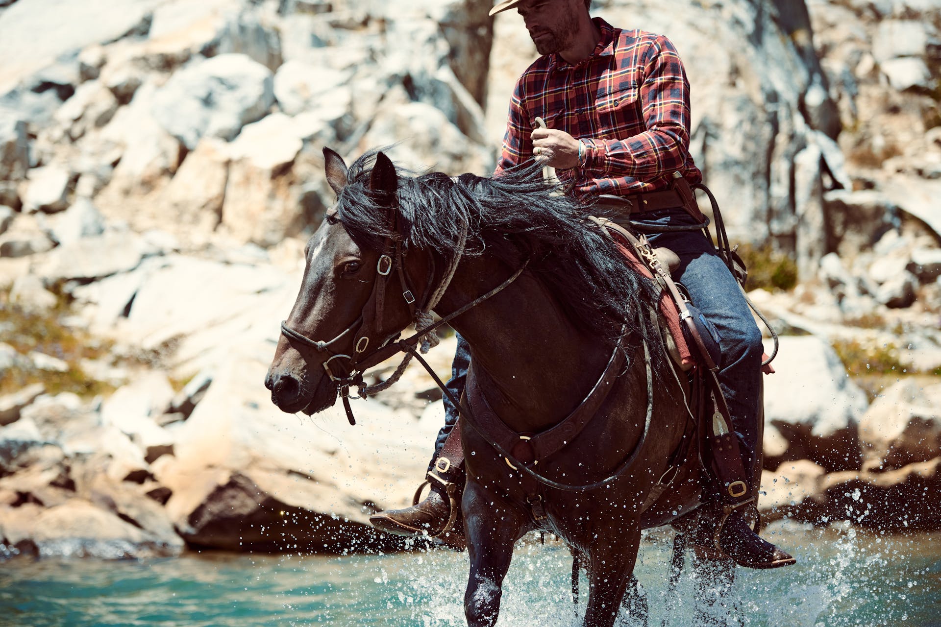 Man riding a horse through water with a Filson Bird & Trout knife in a sheath on his belt