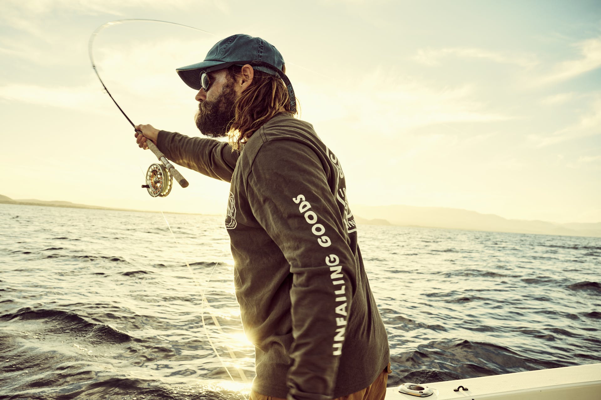 Man fly fishing on a boat wearing a Filson Long Sleeve Pioneer Graphic T-Shirt